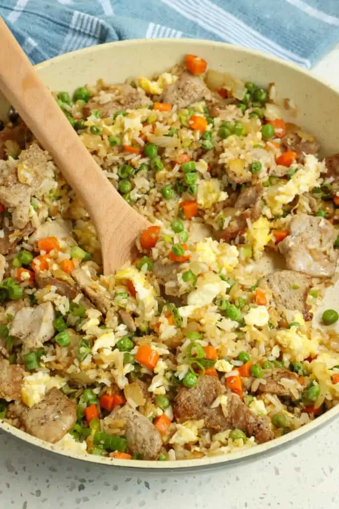 Skip the takeout and make this tasty Pork Fried Rice with pork tenderloin, onions, peas, carrots, eggs, and green onions in perfectly seasoned fried rice. 