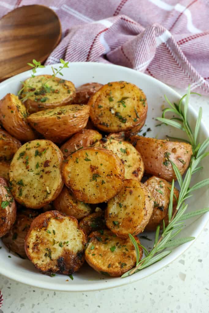 Tasty Roasted Red Potatoes are made simple with minced garlic, kosher salt, fresh ground black pepper, and fresh herbs like thyme, rosemary, and Italian Parsley.  