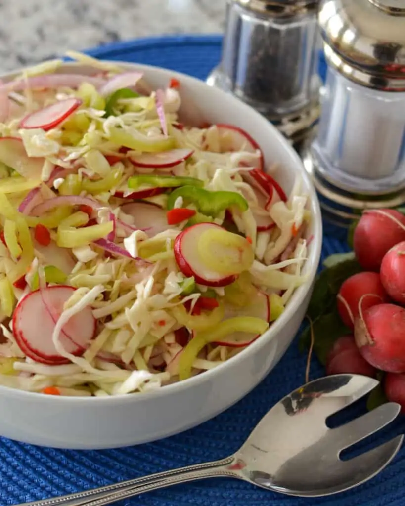 This tasty vinegar cabbage coleslaw is flavor packed with peppers, red onions, radishes, pimentos and diced jalapenos.