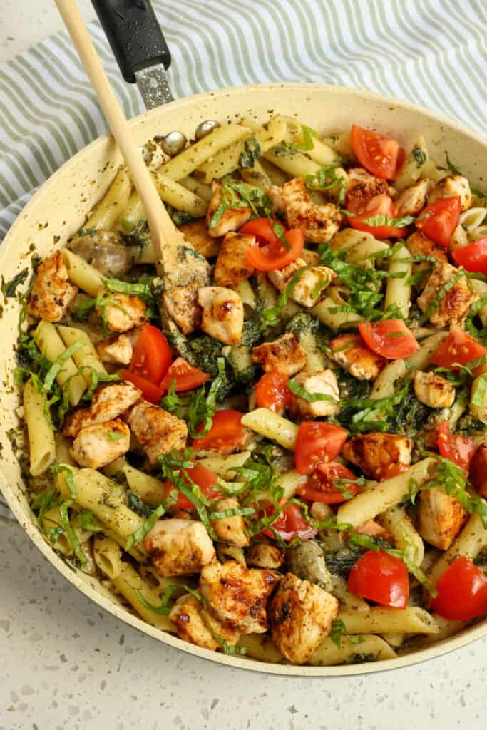 Quick and easy Chicken Pesto Pasta combines golden brown chicken pieces with fresh sauteed mushrooms and spinach, tomatoes, and penne pasta all tossed in pesto sauce.