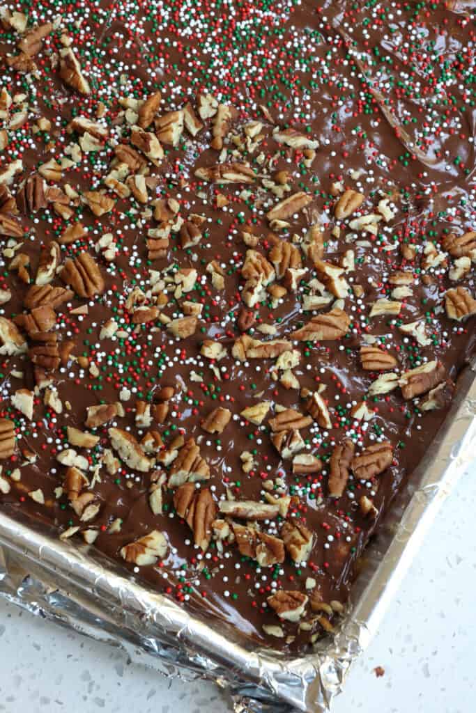 Top with sprinkles or chopped nuts. Let the candy sit on the counter for a few minutes to cool and then pop it in the freezer until it is hard. 