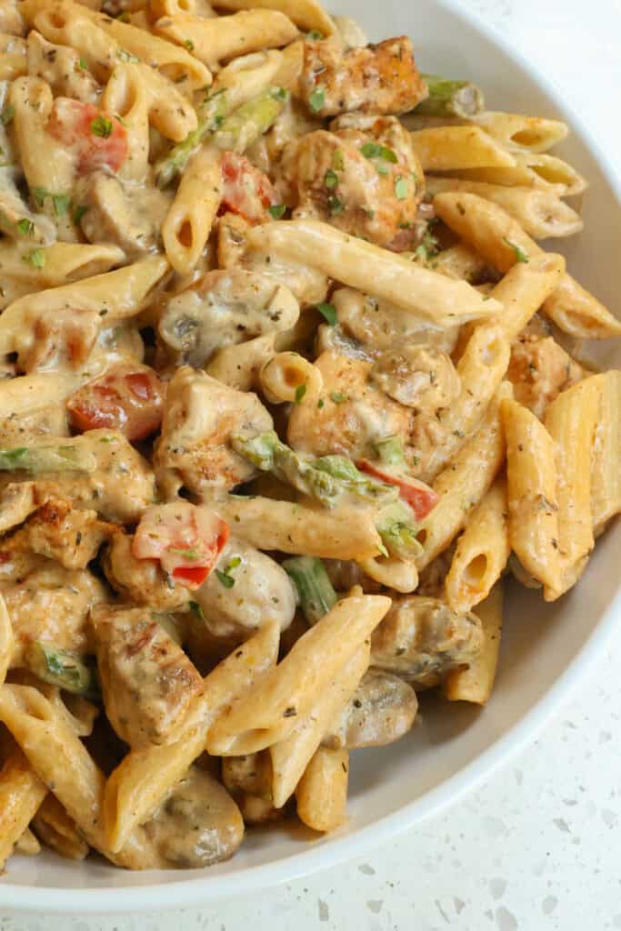 Flavor-packed Cajun Chicken Pasta is made with seasoned browned chicken pieces, sliced white button mushrooms, red bell pepper, and fresh asparagus in a creamy pasta sauce seasoned with homemade Cajun seasoning.