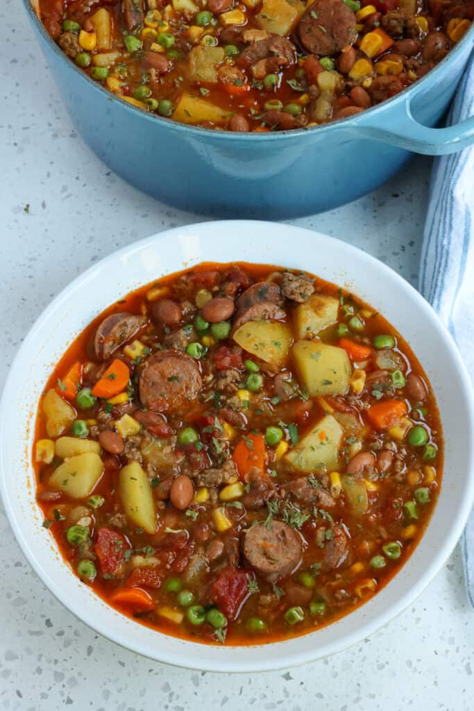 An easy hearty soup with bacon, ground beef, smoked sausage, onions, carrots, garlic, tomatoes, corn, and potatoes in a perfectly seasoned broth with chili powder, cumin, and smoked paprika.