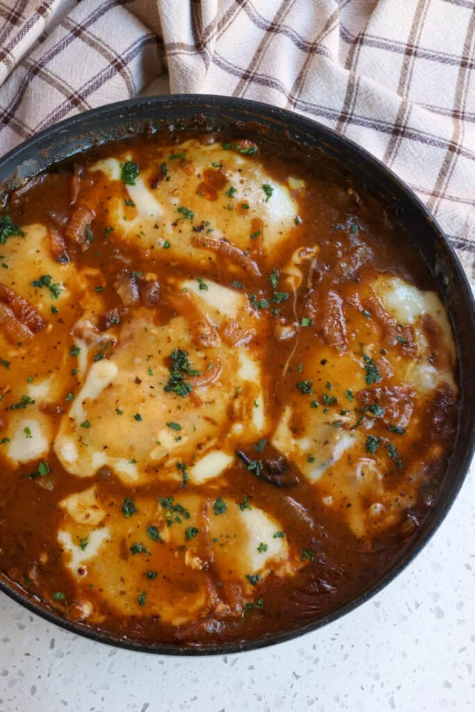 French Onion Chicken sono cotolette di pollo scottate in padella, affogate in una ricca salsa di cipolle francesi e condite con parmigiano, formaggio svizzero e prezzemolo fresco.
