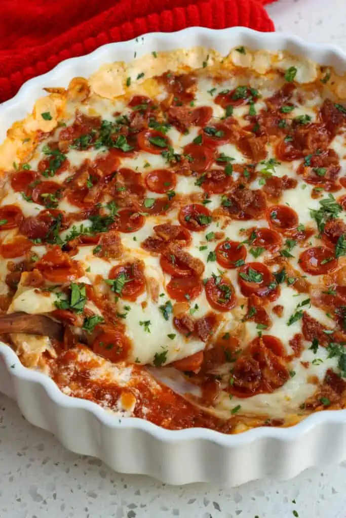 A quick and easy tasty hot cheesy pizza dip made with three different kinds of cheese, a handful of common pantry spices, pepperoni, and crisp bacon.  