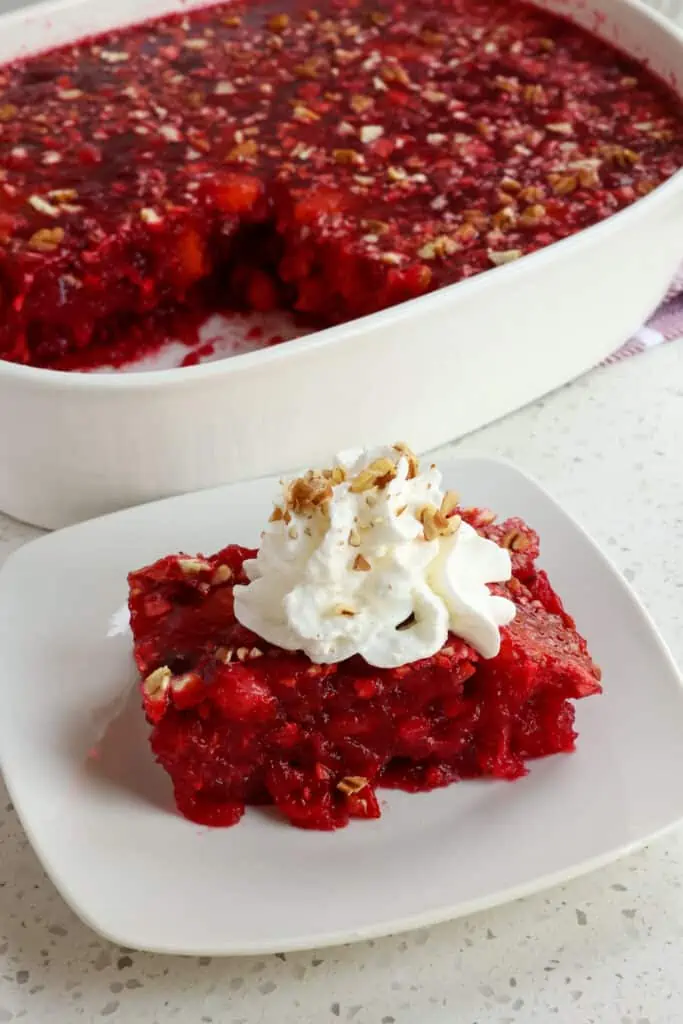 This Cranberry Jello Salad combines simmered fresh cranberries, mandarin oranges, pineapple, and buttery sweet pecans or walnuts into a festive jello salad.