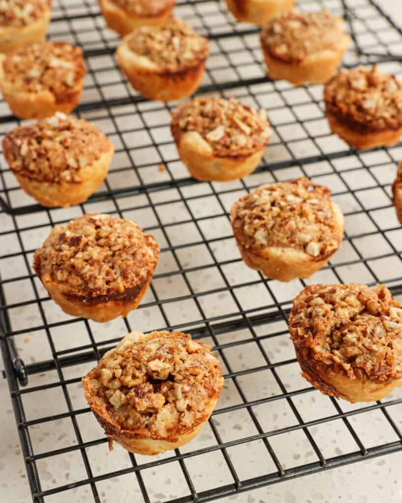 Freshly baked pecan tassies cooling on wire rack.