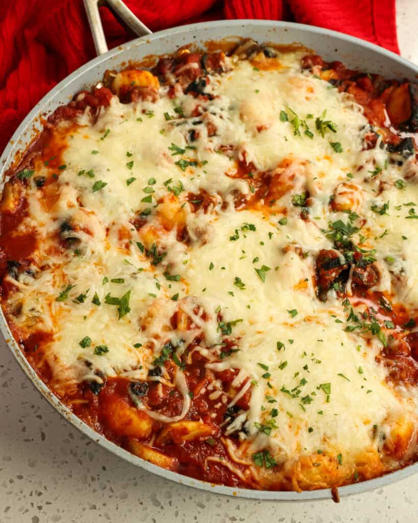 An overhead shot of the baked gnocchi in the skillet with parsley on top.