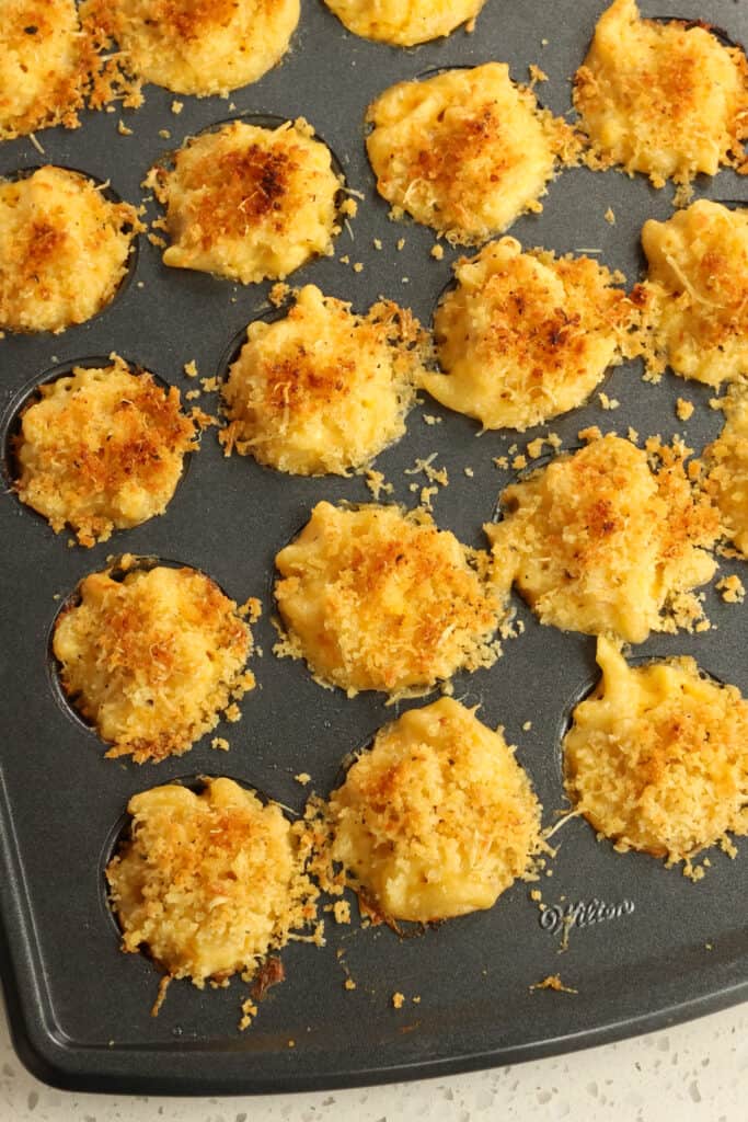 Delicious mac and cheese bites topped with creamy cheddar sauce and crunchy panko breadcrumbs and parmesan cheese. 