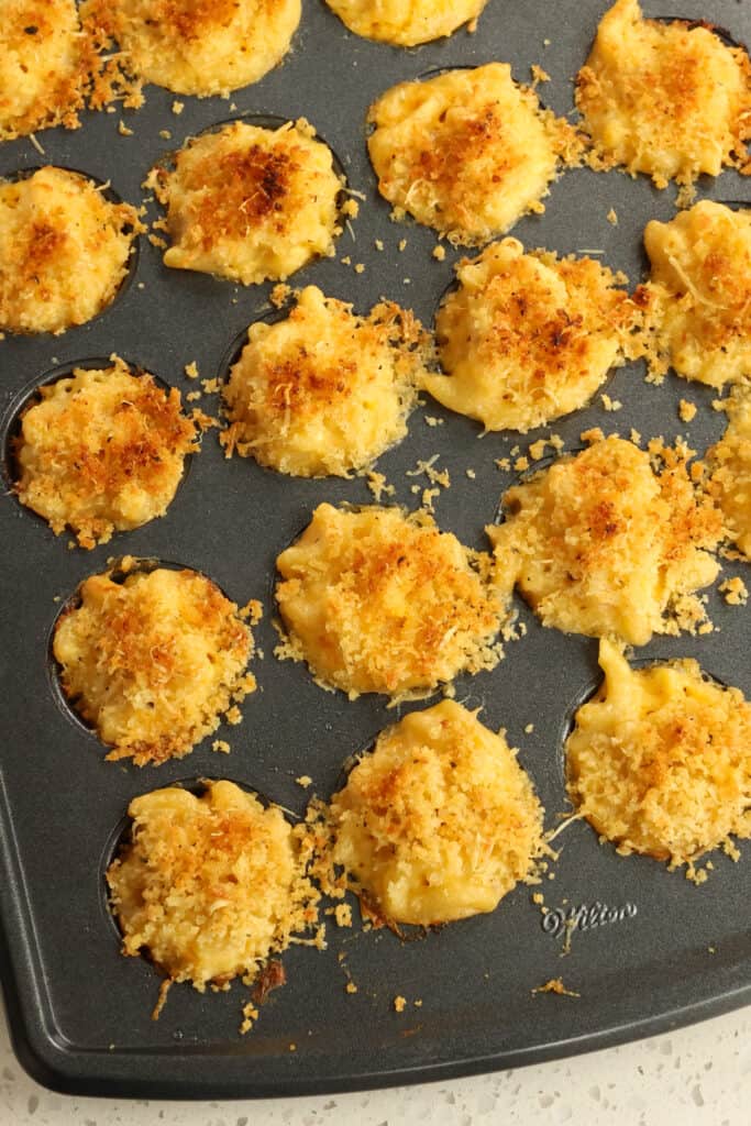 Delicious mac and cheese bites topped with creamy cheddar sauce and crunchy panko breadcrumbs and parmesan cheese.