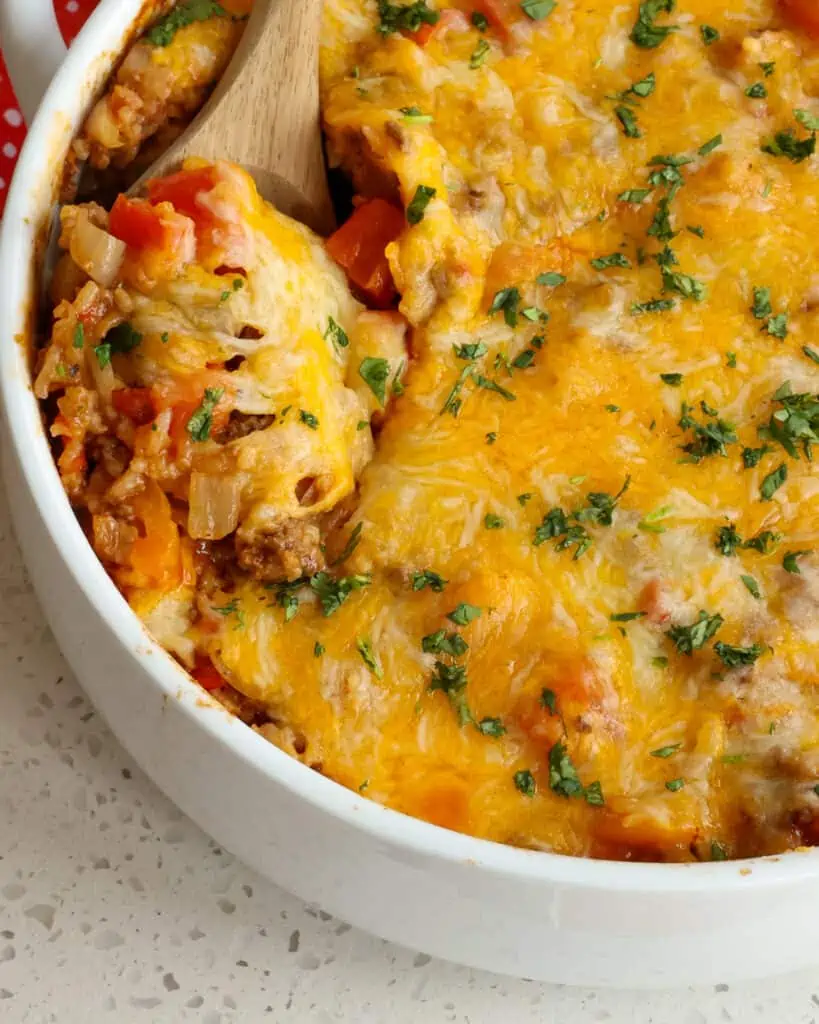 This quick and easy Stuffed Pepper Casserole Recipe combines ground beef, onions, bell peppers, fire roasted tomatoes, and rice all cooked in a perfect blend of spices and covered in melted cheddar cheese and Monterey Jack cheese.  