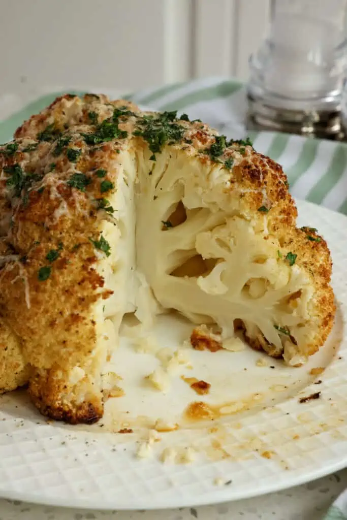 Easy and delicious Whole Roasted Cauliflower seasoned with garlic powder, thyme, rosemary, and fresh Parmesan cheese and oven-roasted to perfection. 