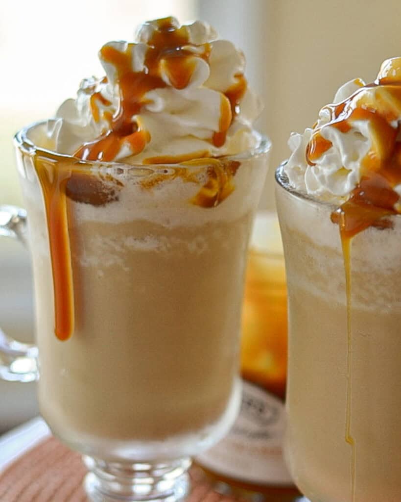 A close up view of caramel frappuccino in a glass mug. 
