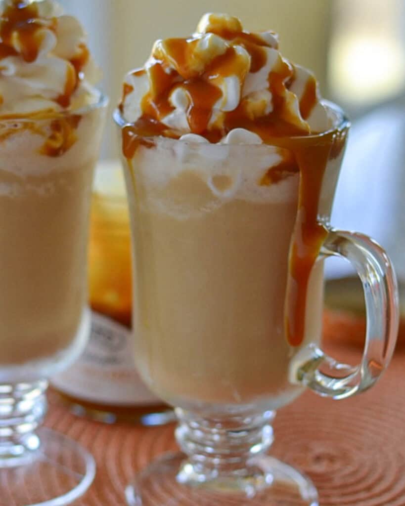 A close up view of two caramel frappuccino topped with whipped cream and caramel topping. 