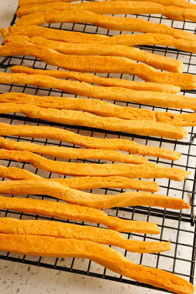 Cheese straws cooling on a wire rack. 