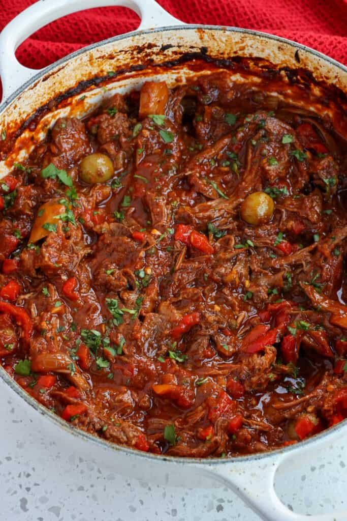 This flavor-packed Ropa Vieja combines tender, slow-cooked chuck roast with onions, bell peppers, garlic, green olives, pimentos, and capers into a tasty tomato-based sauce seasoned with paprika and cumin.