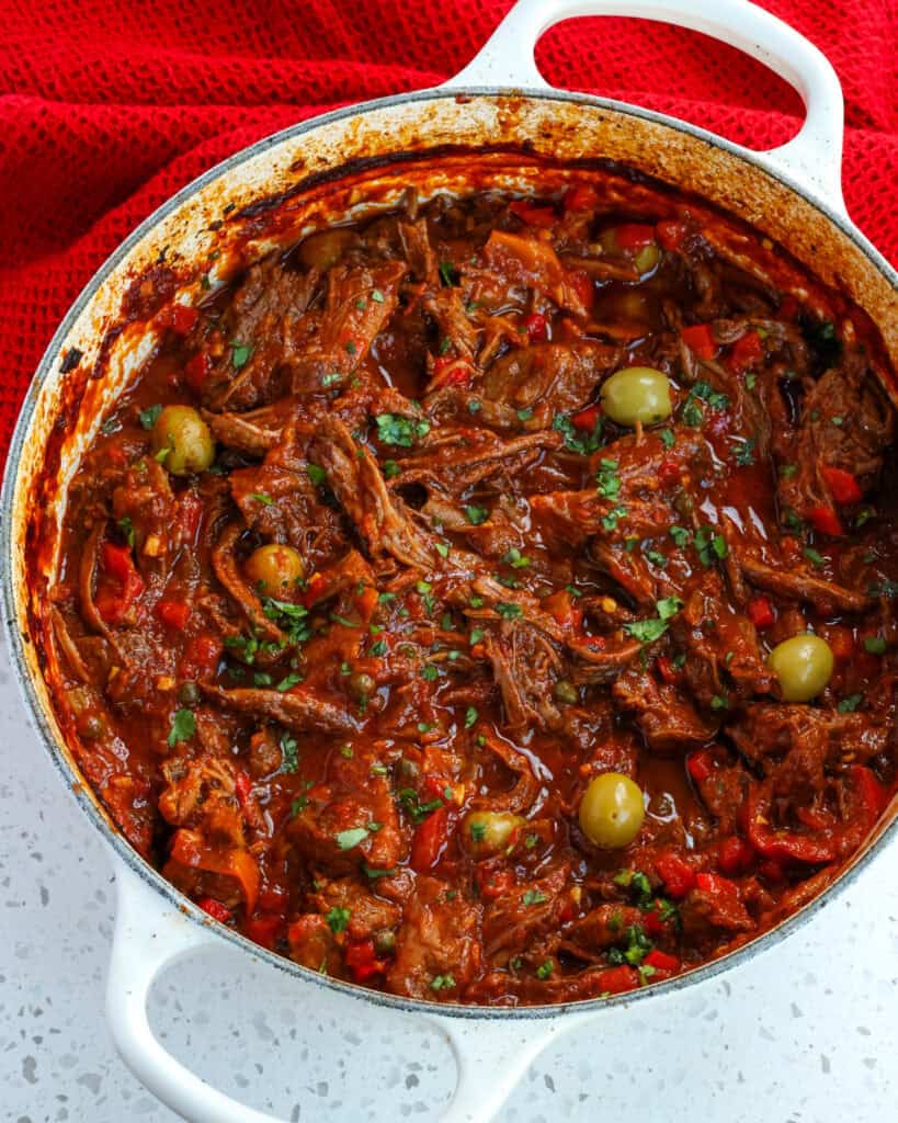 An overhead view of a Dutch oven full of ropa vieja. 