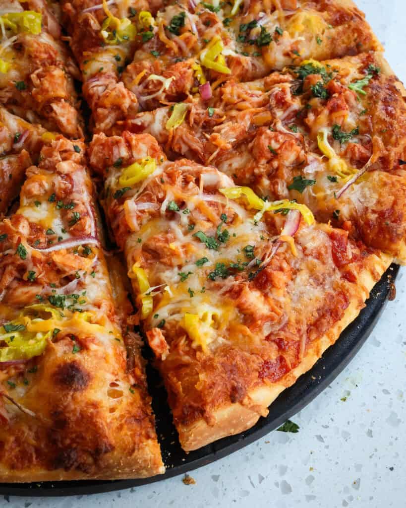 BBQ Chicken Pizza cut into slices on the pizza stone. 