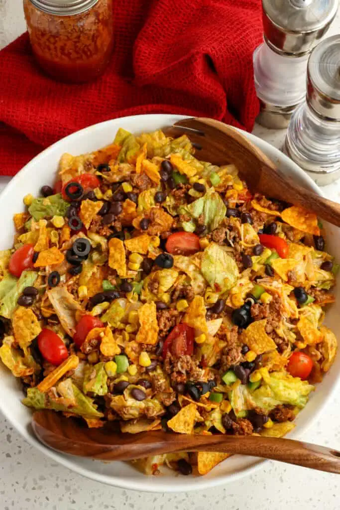 Doritos Taco Salad is a delectable combination of iceberg lettuce, tomatoes, green peppers, black beans, corn, black olives, seasoned ground beef, shredded cheddar jack cheese, and crunchy Doritos in a homemade tangy sweet Catalina dressing