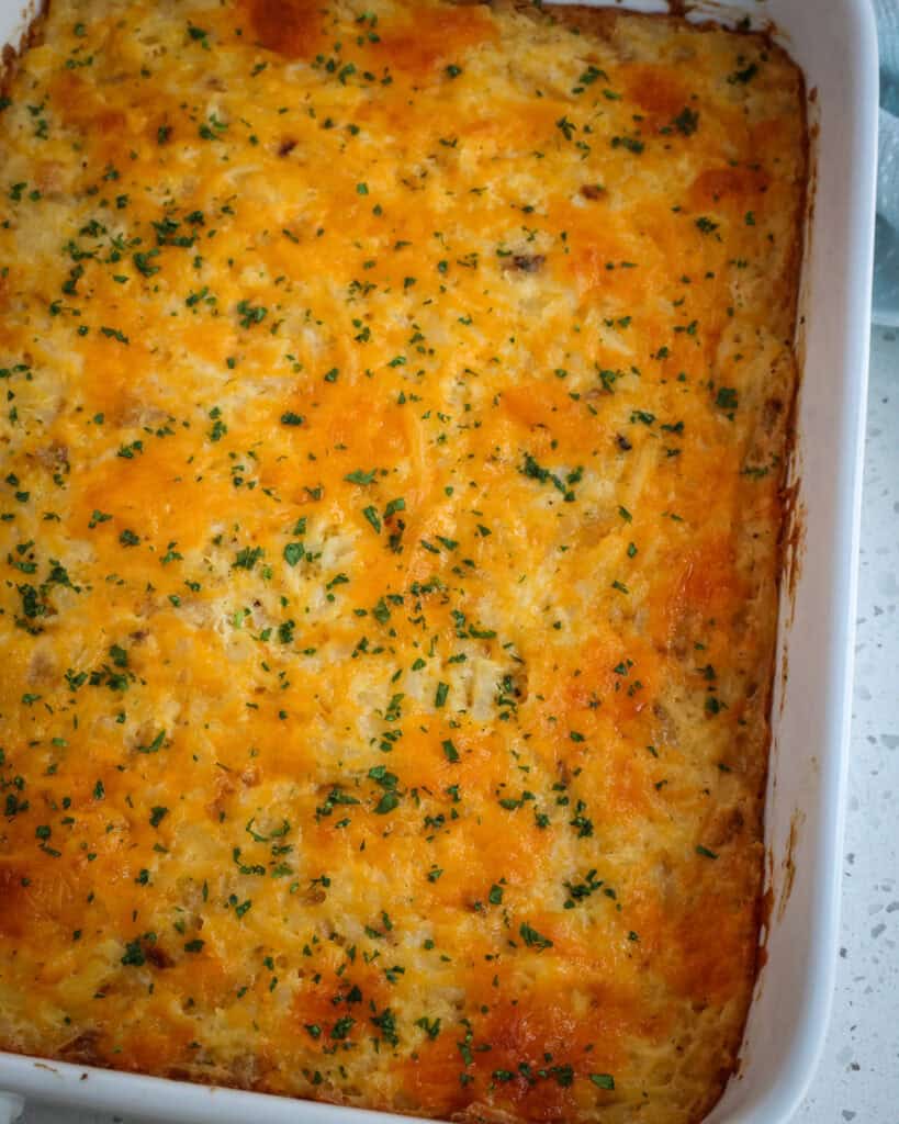 Full Hashbrown Casserole close up with chopped fresh herbs.