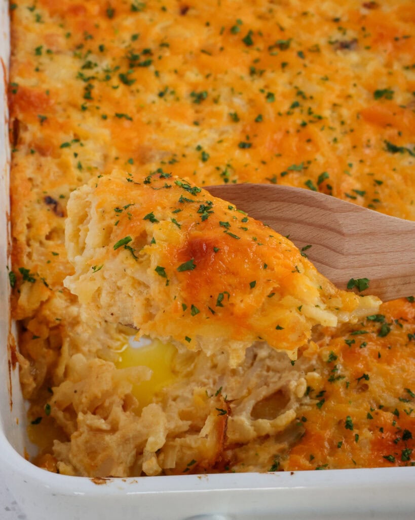 Hashbrown Casserole on a spoon close up with fresh chopped herbs on top.