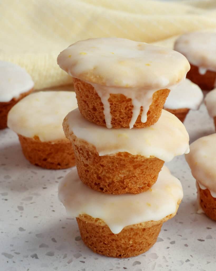A stack of iced lemon blossoms with a yellow striped kitchen towel in the background.