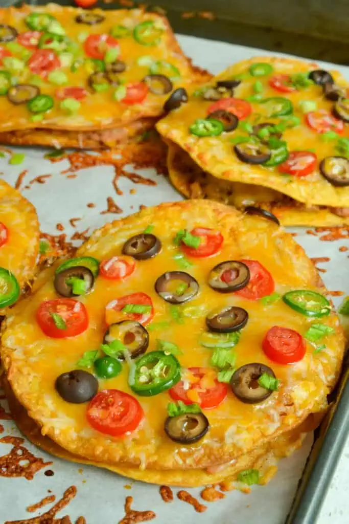 Mexican Pizzas stuffed with refried beans and taco seasoned ground beef then topped with oodles of cheese and tomatoes. 