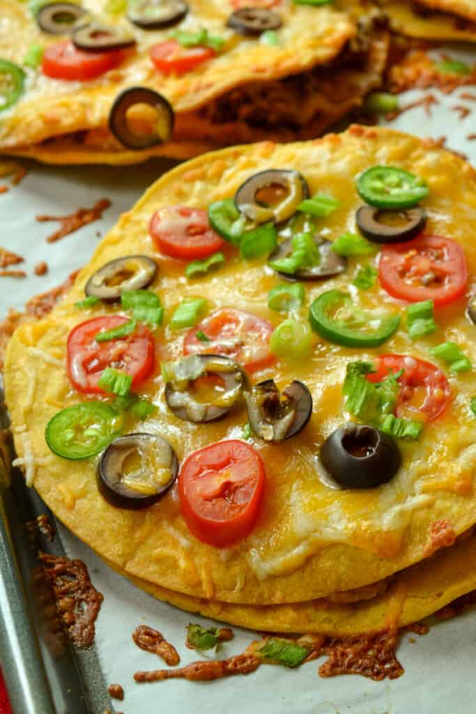 These Mexican pizzas are double decker crispy fried tortilla pizzas stuffed with seasoned beef, refried beans, and cheese. 
