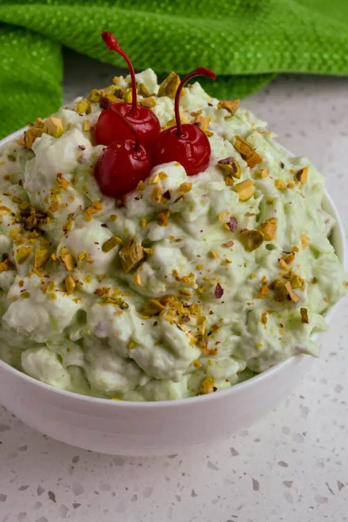 This classic Watergate Salad Recipe, also known as Pistachio Delight and Green Fluff, is a fresh blast from the past with the flavors of crushed pineapple, pistachio pudding, pistachio nuts, mini marshmallows, and fresh whipped cream.  
