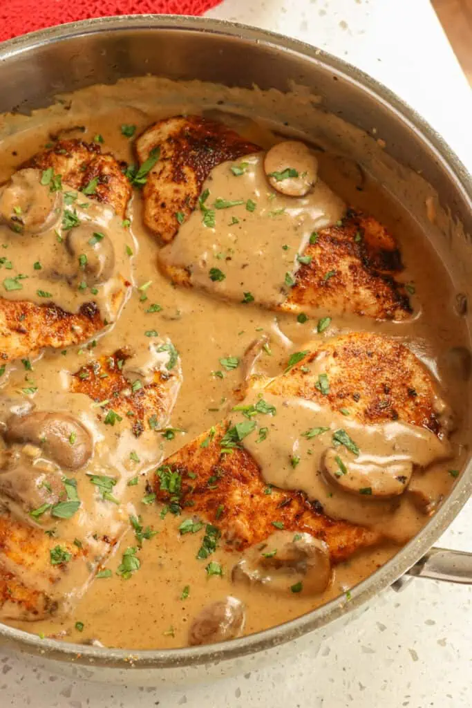 This Cajun Chicken is chicken breasts rubbed with Cajun seasoning and pan-seared, with browned and seasoned cremini mushrooms, all in a luscious creamy cajun sauce made without heavy cream.