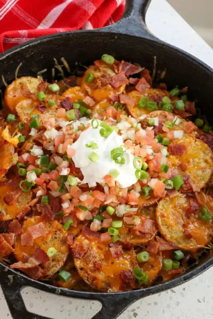 Fun and easy Irish nachos made with crispy potatoes rounds, plenty of sharp cheddar cheese, crumbled bacon, and your choice of yummy toppings like green onions, Pico de Gallo, and sour cream.