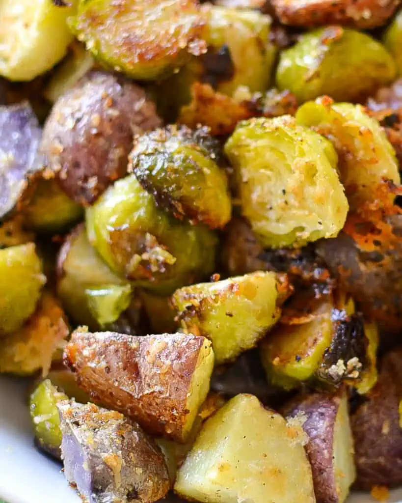 These Roasted Potatoes and Brussels Sprouts are the perfect side dish recipe made with fresh brussels sprouts, red and purple potatoes, and fresh Parmesan cheese.