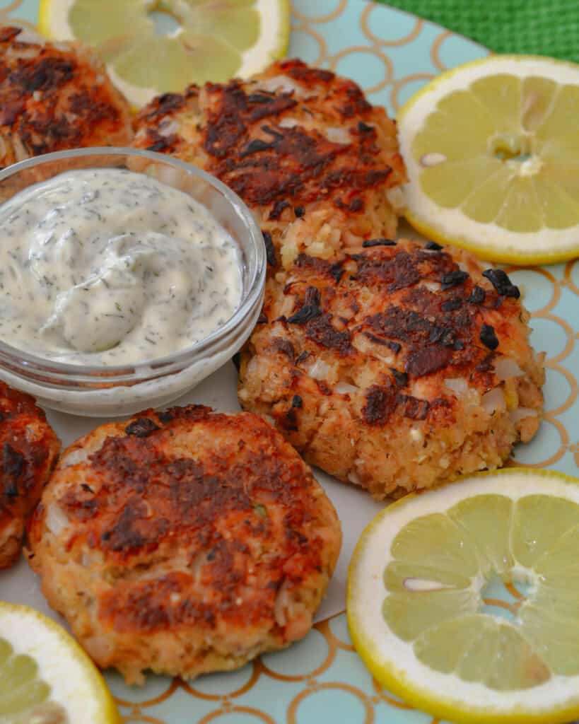 Best Salmon Patties Smoked sausage patties on a plate with lemon slices and a small bowl of dill mayonnaise.