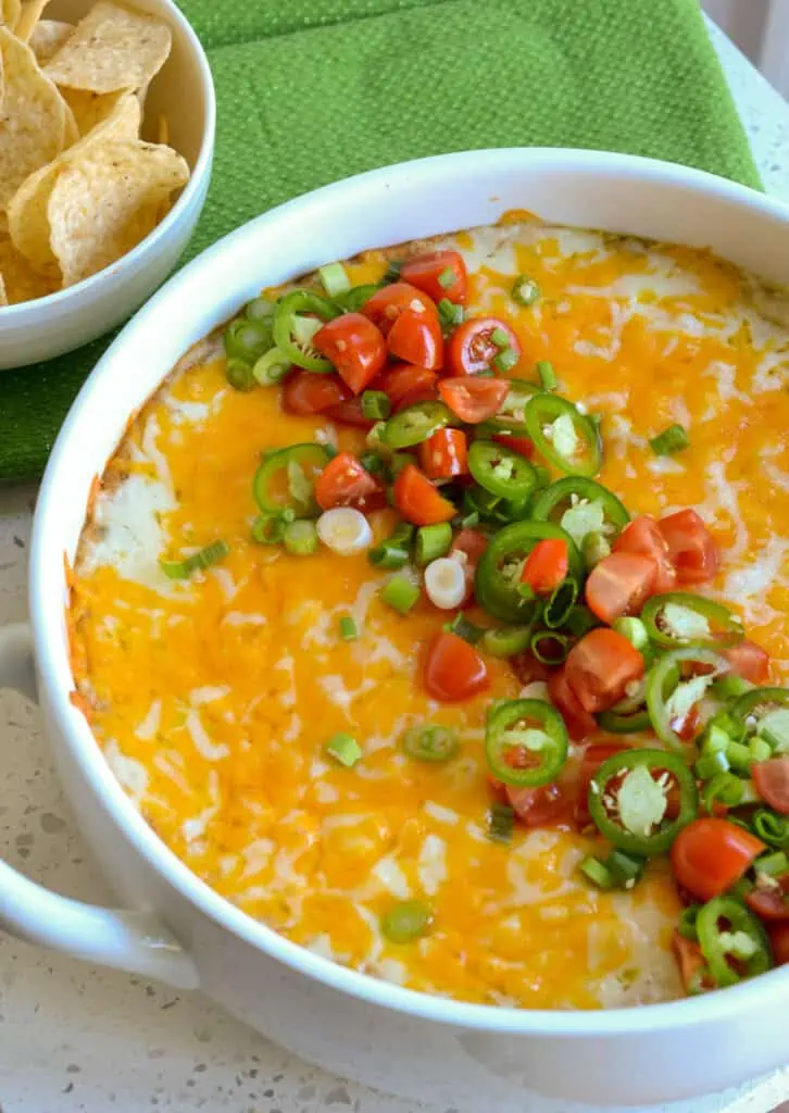 This recipe for Warm Bean Dip is a real crowd-pleaser with creamy refried beans mixed with cream cheese, sour cream, green chiles, taco seasoning, and plenty of melted Monterey Jack and cheddar cheese. 