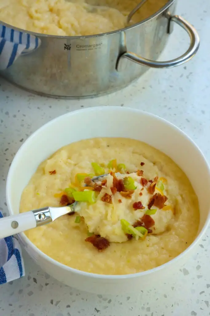 Smooth and Creamy Cheese Grits garnished with bacon and green onions is the perfect side dish for eggs,  andouille sausage, barbecued ribs, and sauteed shrimp. 