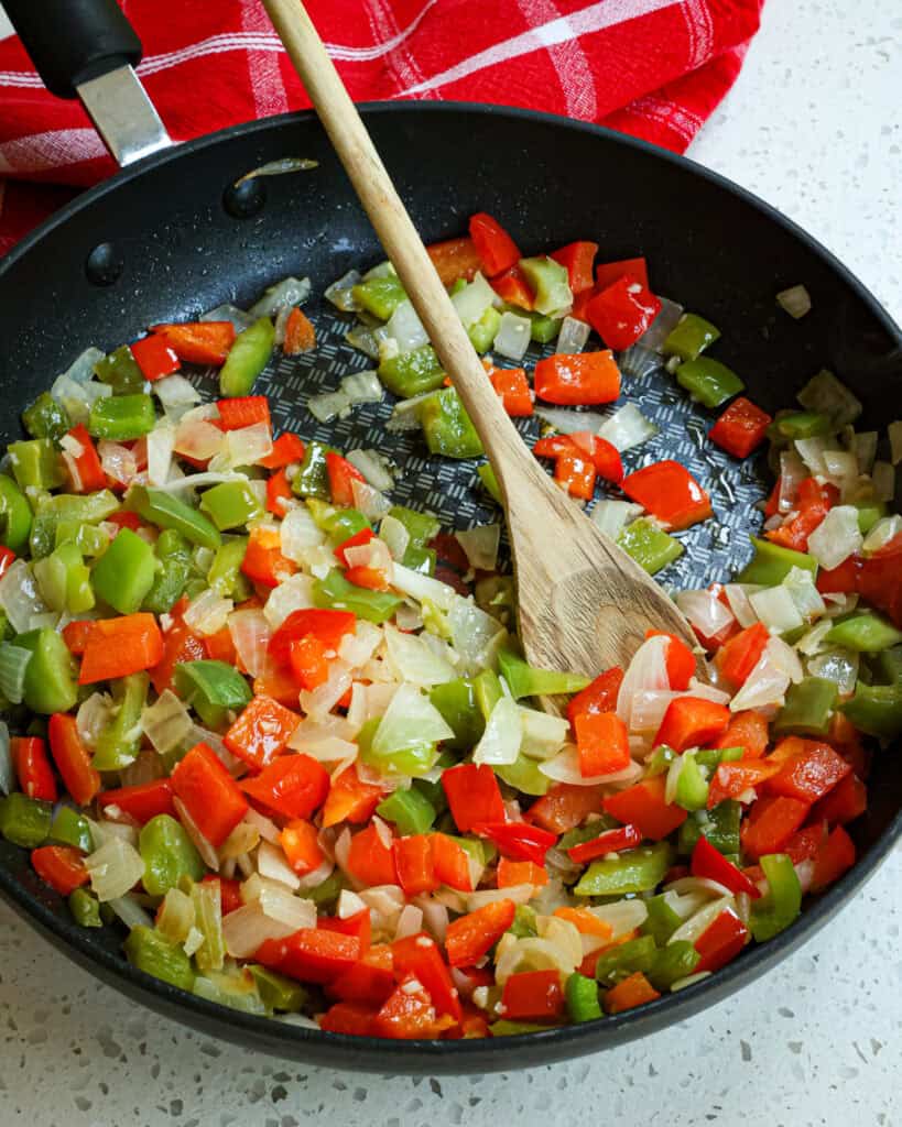 Add the onions and bell pepper and cook until they are soft. Reduce the heat to low and add the garlic, cooking for 1 minute while stirring constantly. 