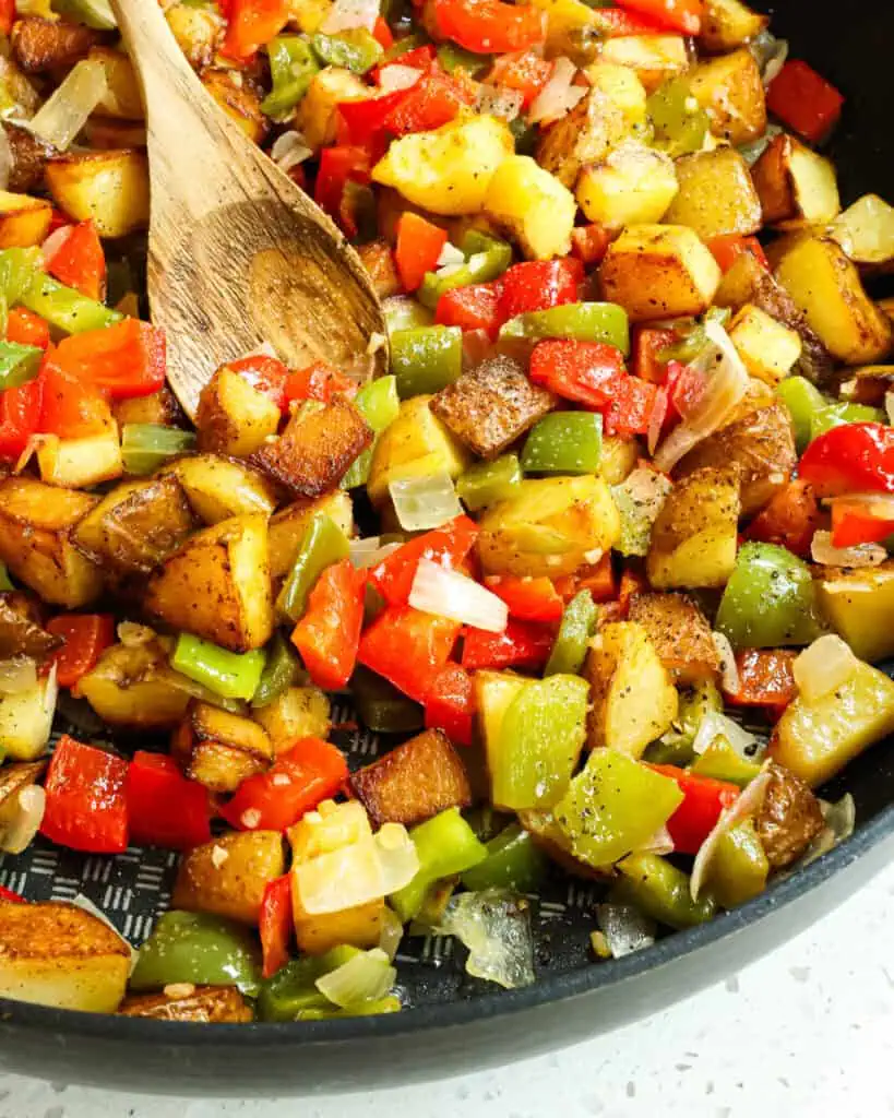 A close up view of potatoes o'brien in large black skillet. 