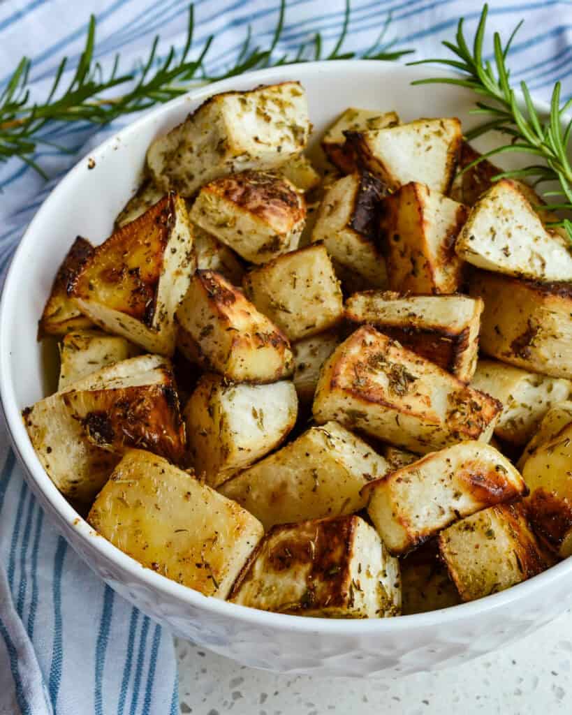 Roasted Turnips in a white bowl with rosemary sprigs on the side.