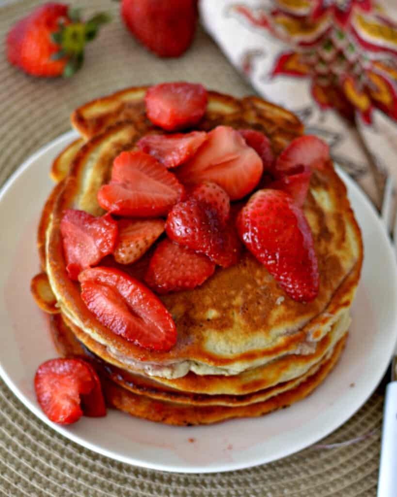 Light, fluffy, and golden pancakes topped with fresh strawberries and a sweet strawberry syrup