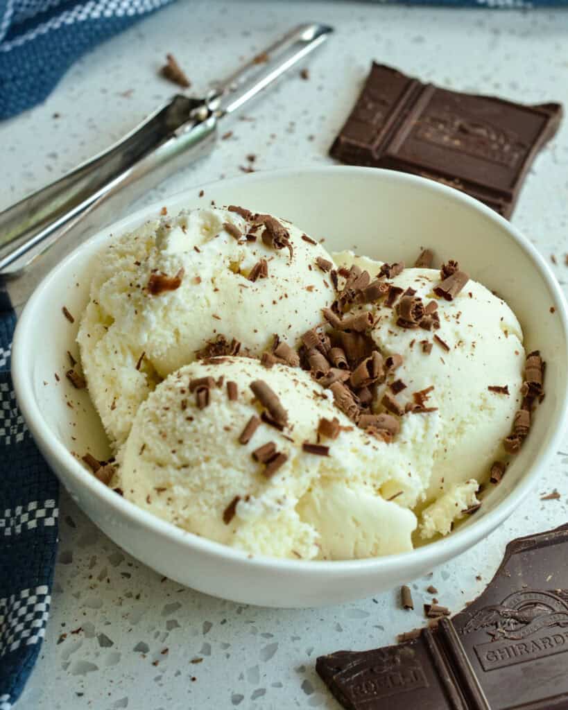 Vanilla Ice Cream in a small white bowl topped with chocolate shavings.