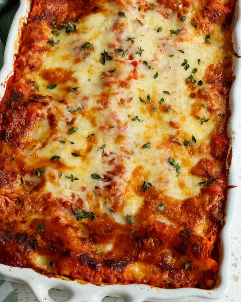 A close up of Vegetable Lasagna before cut. Golden brown cheese and topped with herbs.