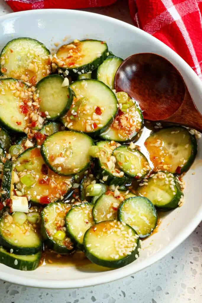 Asian cucumber salad in a bowl with a wooden spoon. 
