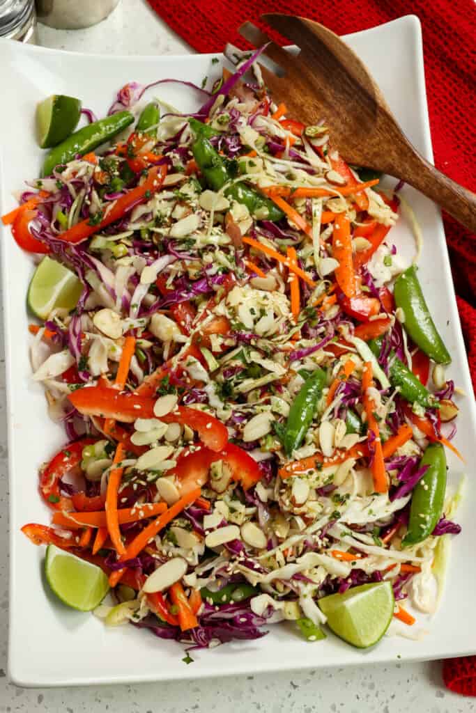 This flavor-packed Asian Salad combines cabbage, red bell peppers, carrots, sugar snap peas, almonds, green onions, toasted sesame seeds, and cilantro, all tossed in a sesame ginger salad dressing. 