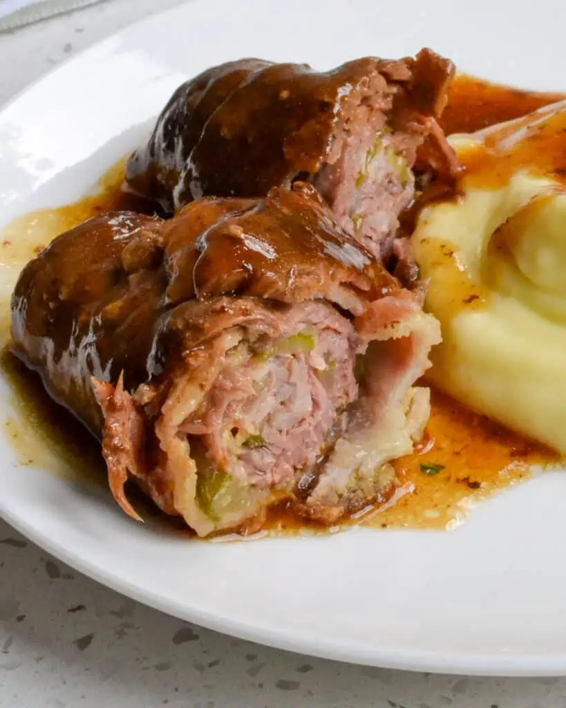 German Beef Rouladen Recipe combines thin slices of top round steak stuffed with spicy brown mustard, bacon, pickles, and onion, all browned and smothered with a mouthwatering easy-to-make beef gravy.