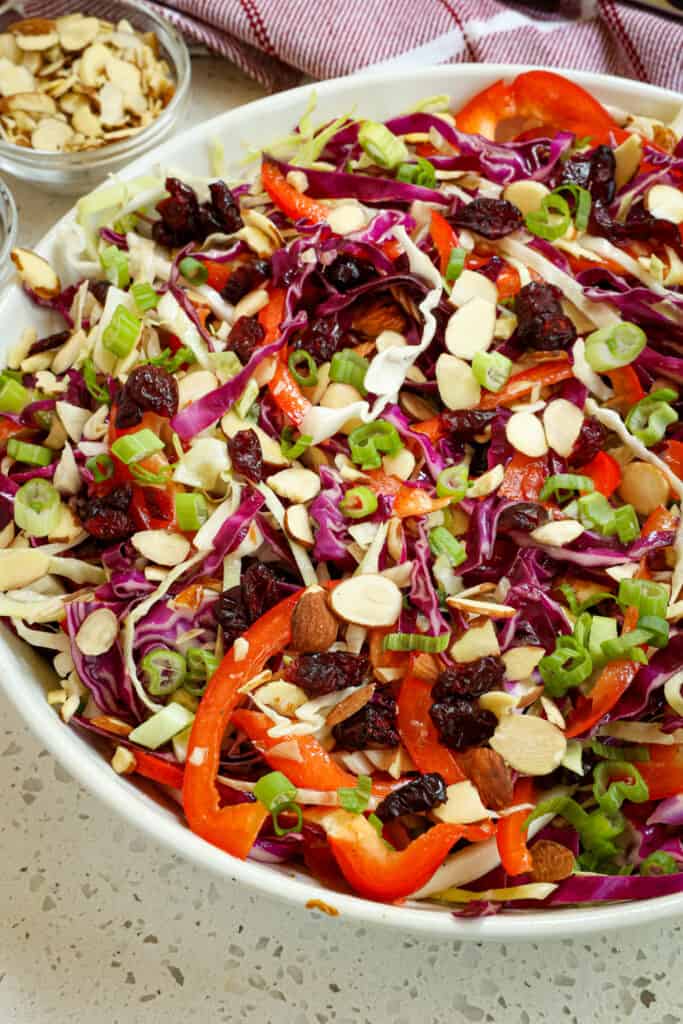 A quick and easy Cabbage Salad with red bell pepper, thinly sliced red onions, sliced almonds, and dried cranberries, all in a sweet and tangy honey mustard ginger vinaigrette. Add some grilled chicken or shrimp and make it a full meal entree.