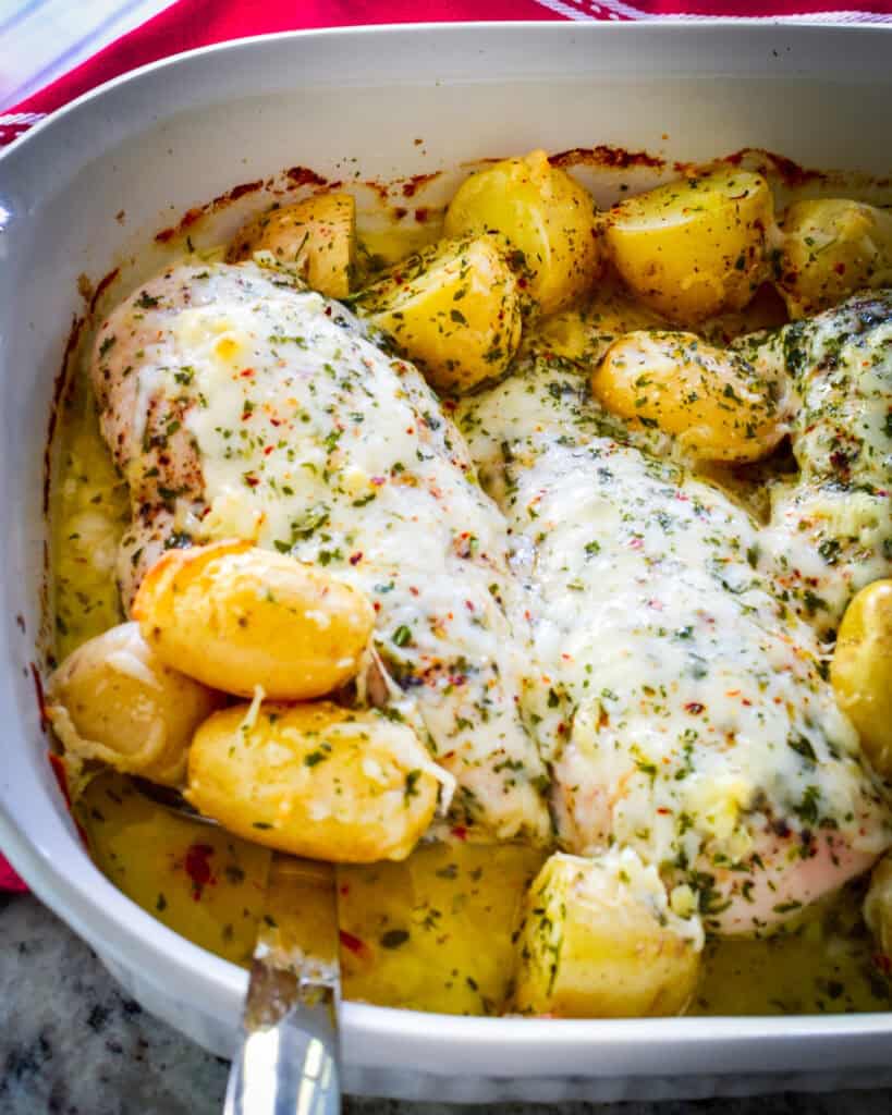 An overhead view of garlic butter chicken and potatoes in a casserole dish. 