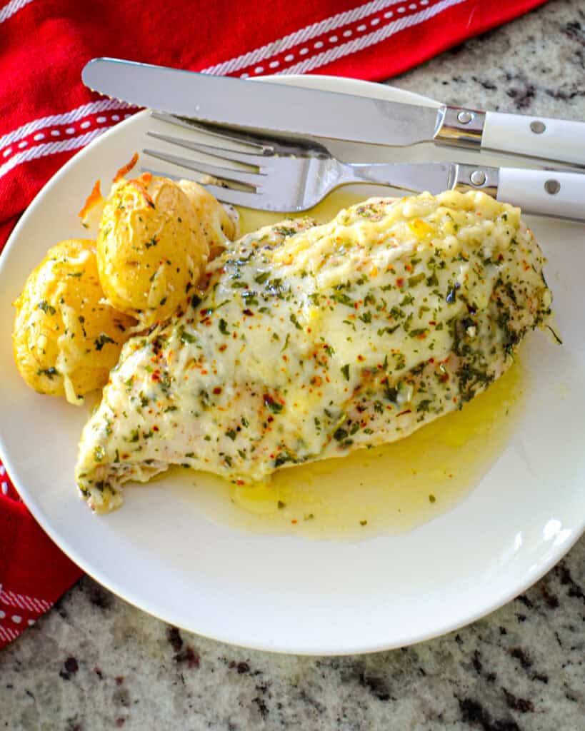 An overhead view of garlic butter chicken on a plate with potatoes. 