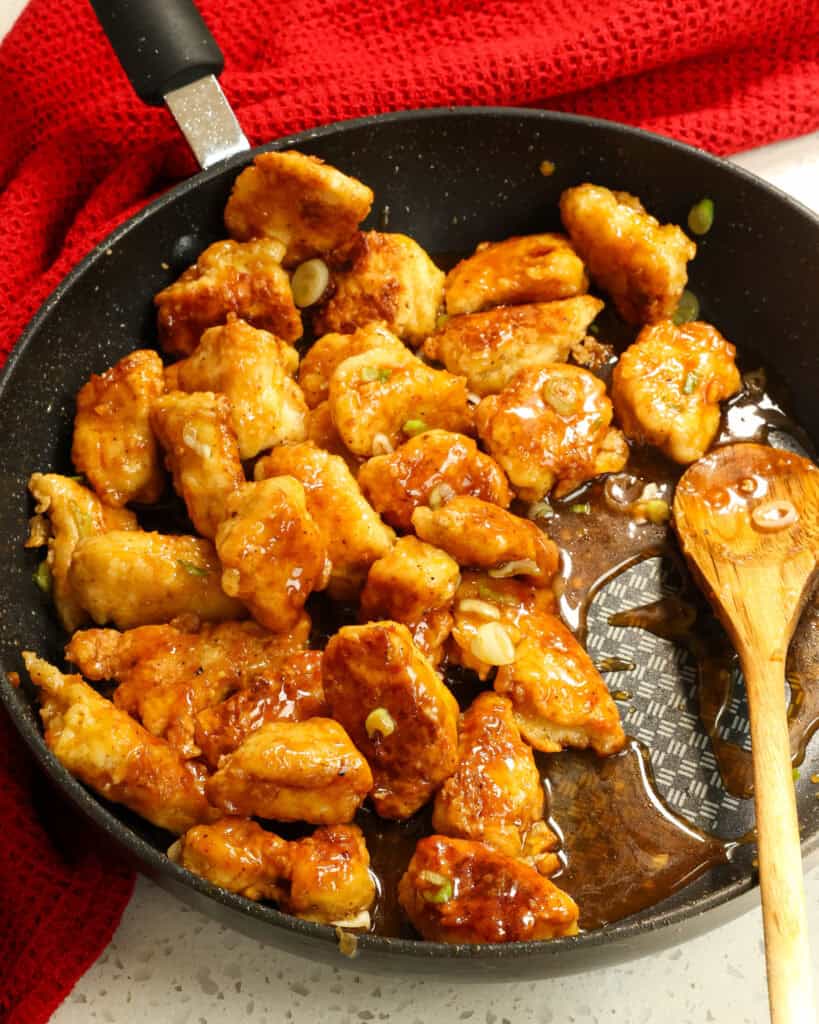 A large black skillet full of honey garlic chicken. 