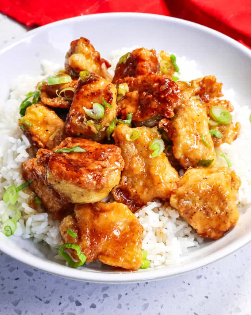 Honey garlic chicken over rice in a white serving bowl. 