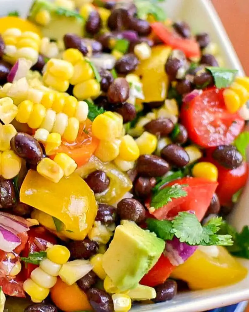 Fresh Black Bean and Corn Salad is black beans, sweet corn, tomatoes, avocado, red onion, and minced jalapenos in a light lime vinaigrette. 
